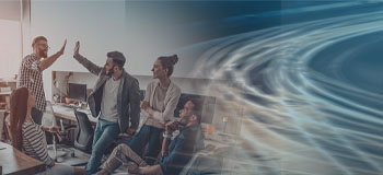Group of people in a modern office environment, some sitting, others standing, two people giving each other a high-five. Abstract, swirling light patterns can be seen on the right side of the image.
