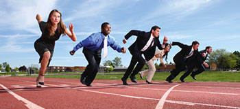 Five people in business attire lined up on a running track in starting positions, symbolizing competition or readiness.