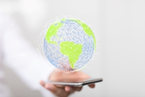 Digital globe with green continents and blue network lines hovering above a smartphone.