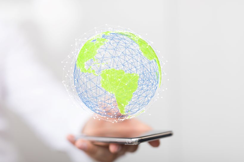 Digital globe with green continents and blue network lines hovering above a smartphone.