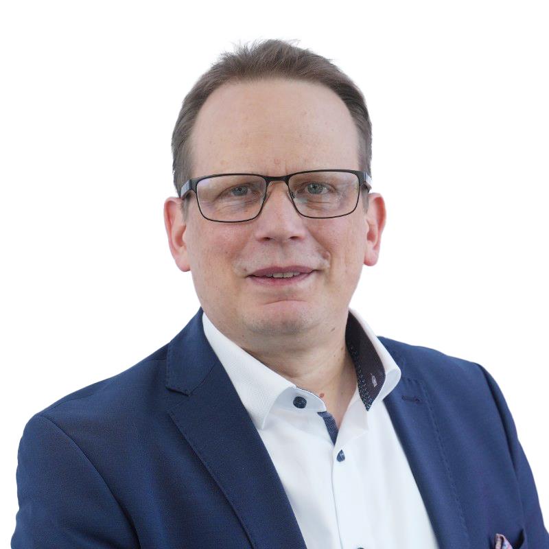 A professional portrait of a person wearing a navy blue suit jacket and a white dress shirt, photographed against a clean white background. Image prepared for ITVT corporate branding and materials.