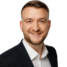 Professional portrait-style photo of a person wearing a dark suit jacket and a white collared shirt, used for ITVT corporate materials.