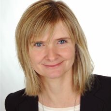 Professionelles PortrÃ¤tfoto einer Person mit schulterlangen blonden Haaren, die einen schwarzen Blazer Ã¼ber einem hellen Oberteil trÃ¤gt, verwendet fÃ¼r ITVT-Unternehmensmaterialien.